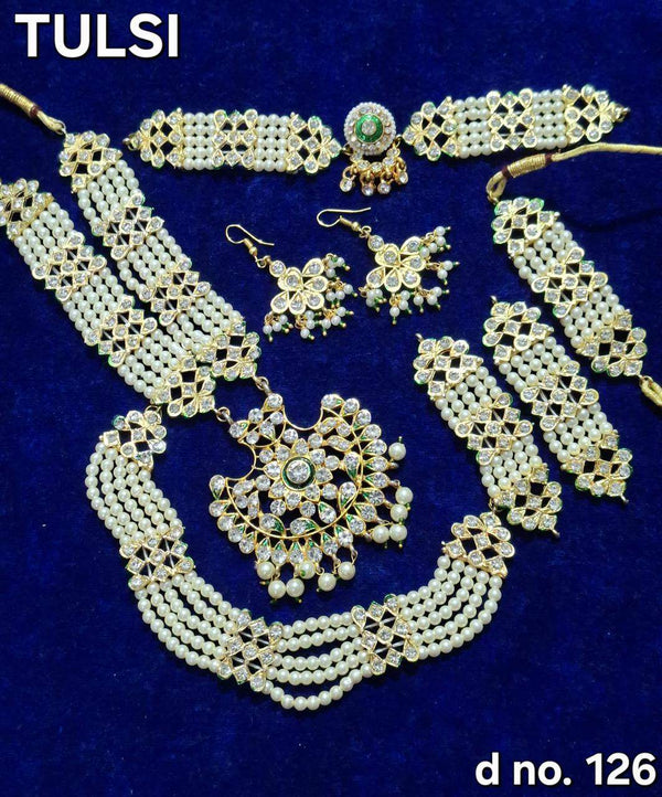 Gold-toned shringar jewellery set with green-stone necklace, earrings, and long chain strands