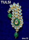 Ornate idol ornament with gold frame, blue stones, green oval center, two green drops