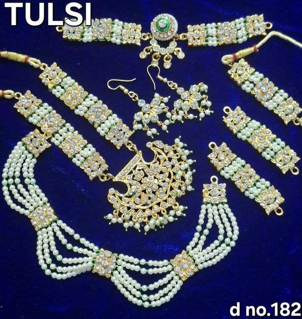 Gold-toned kundan jewellery set with green pendant necklace and dangling earrings