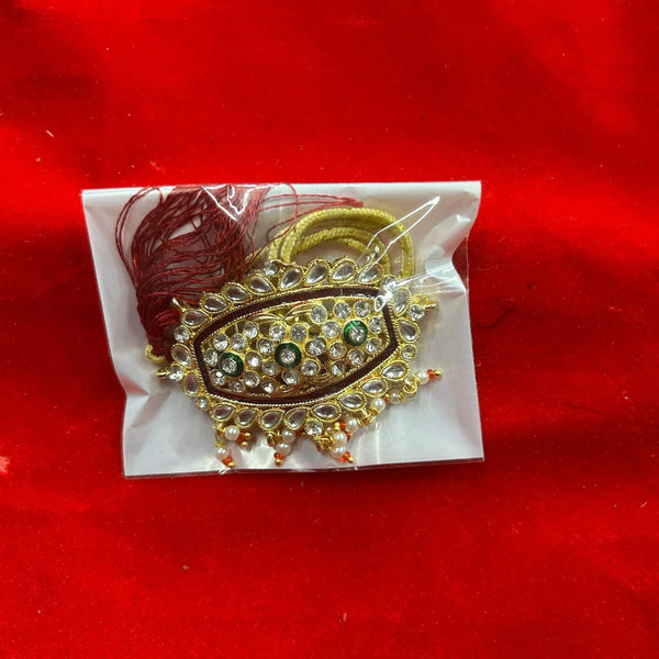 Decorative idol ornament with gold trim and gem-like stones, with red tassel