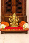 Red velvet pooja aasan cloth with gold embroidered border, laid on a platform
