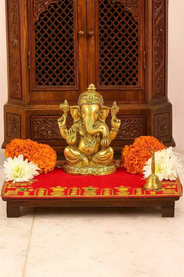 Red velvet pooja aasan cloth with gold embroidered border, laid on a platform
