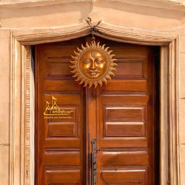 Copper sun face wall hanging centered above a wooden door panel