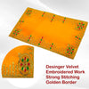 Folded yellow velvet pooja aasan cloth with golden embroidered border and corner motifs