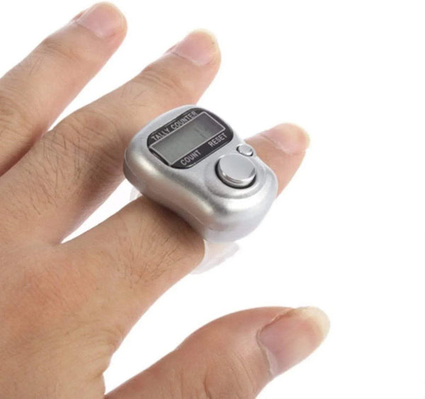 Silver digital finger tally counter ring on a hand, circular button on the side