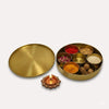 Round brass pooja box lid with open divider tray; diya lamp holder nearby