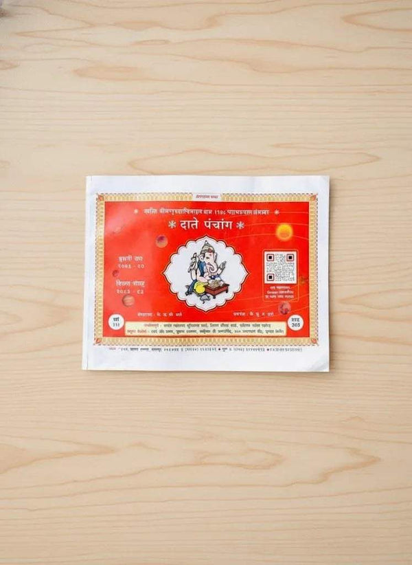 Hindi panchang calendar book with red cover on a light wooden surface