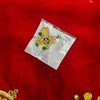 Golden green-stone puja ornament in clear pouch on red fabric