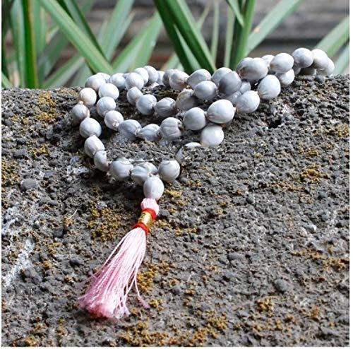 Off-white bead japa mala with pink tassel resting on stone