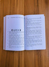 Open Hindi book with two printed pages on a wood tabletop, dense paragraphs and headings