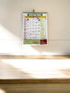Wall-hanging 2025 panchang calendar with date grid and bottom devotional emblem