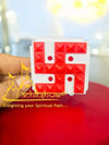 Red swastik pyramid vastu yantra held in hand, square tray with raised blocks