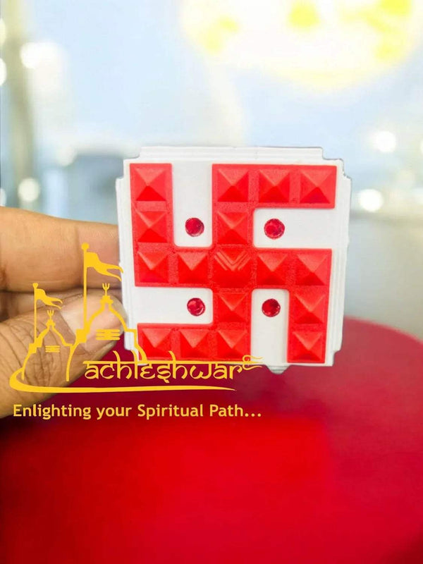 Red swastik pyramid vastu yantra held in hand, square tray with raised blocks