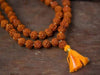 Rudraksha bead mala with orange tassel and small brown spherical beads