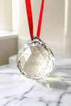 Clear faceted crystal hanging ball with red ribbon, close-up
