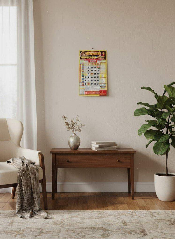 Small panchang wall calendar for 2026 hanging above a wooden console table