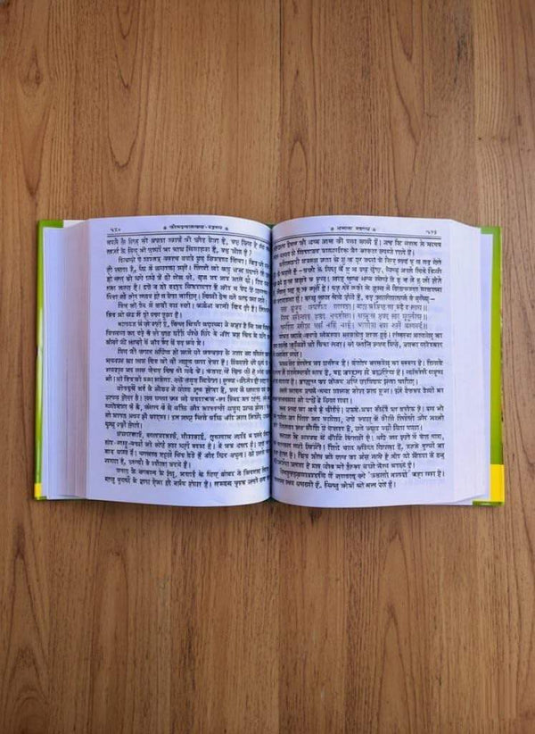 Open Hindi book with two pages of dense printed text on a wooden surface
