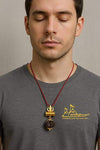 Gold trident pendant with dark rudraksha bead on red cord necklace