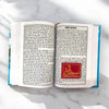 Open book with printed Hindi pages and a red devotional emblem on the right page.