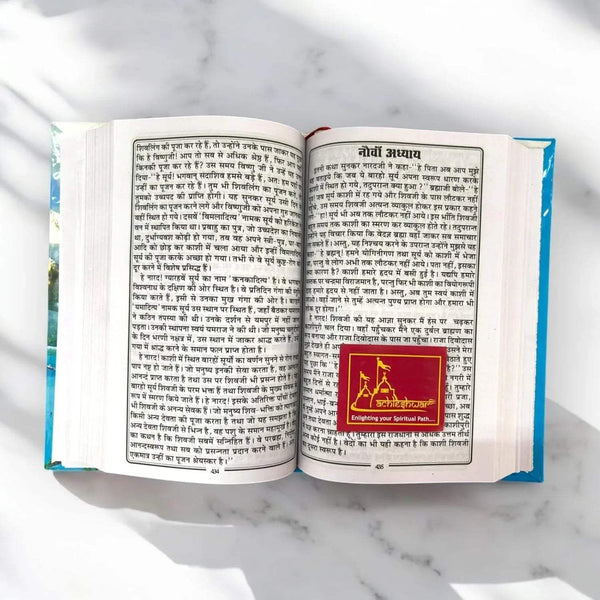 Open book with printed Hindi pages and a red devotional emblem on the right page.