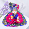 Mini deity idol wearing beaded mala necklace and bright blue and pink headpiece