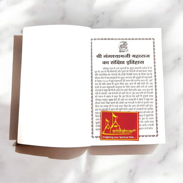 Open spiritual booklet showing dense Hindi text on cream pages and red path logo
