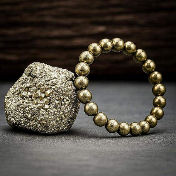 Gold beaded pyrite-style bracelet with spherical metallic beads on a rough stone.
