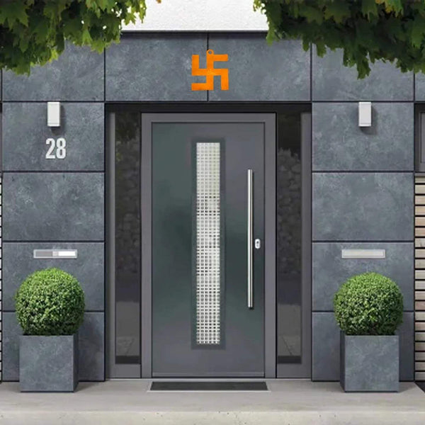 Orange-copper swastik vastu yantra above doorway on a gray wall