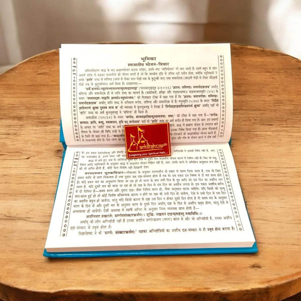 Garuda Purana book open to printed text pages, blue-backed spine visible