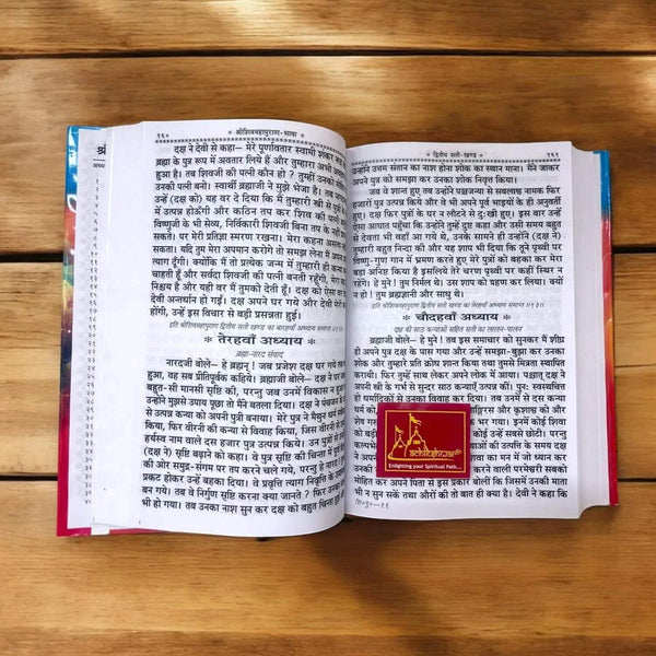 Open devotional book with dense Hindi text and a red square emblem on the right page