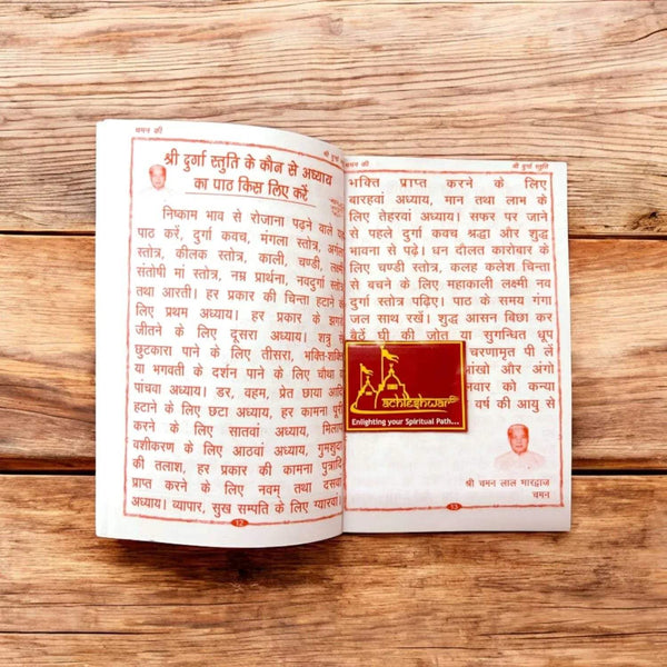 Open devotional book with two pages of red Hindi text and central temple illustration