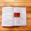 Opened Hindi song book showing dense printed text on left and right pages