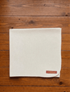 Off-white woolen meditation mat with stitched hem and brand tag on corner
