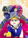 Jeweled deity figurine with blue crown, magenta veil, and gold and jewel accents