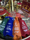 Assorted attar pouches in blue, orange, maroon, and green on a metal tray