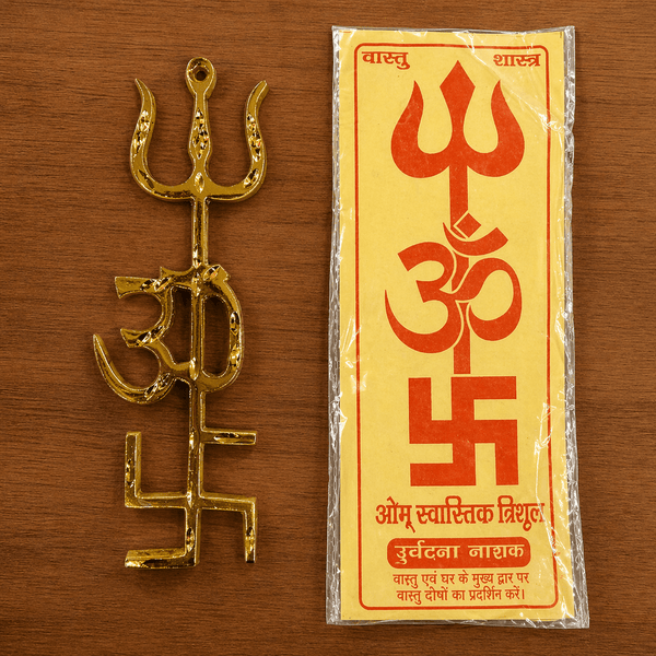 Gold trishul yantra beside a wrapped packet showing Om and printed text.