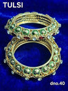 Gold bangles with green stones and red accents, ornate stacked design