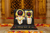 Marble dust idol statue, close view of two seated figures in white and gold on black base