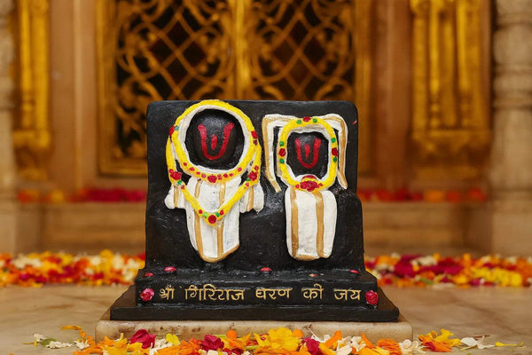 Marble dust idol statue, close view of two seated figures in white and gold on black base