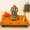Orange pooja asan cloth with green vine and gold-trimmed embroidered border, on display