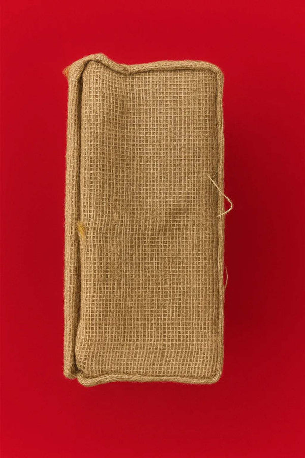 Jute idol cradle with stitched fabric cover and tied closure, light tan