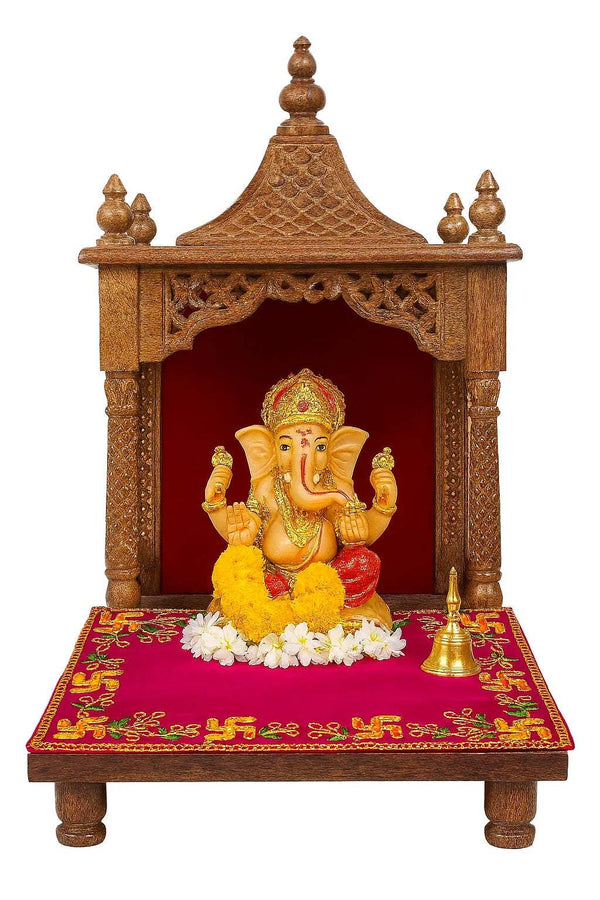 Pink pooja asan mat on wooden altar stand, with golden border and embroidered motifs.