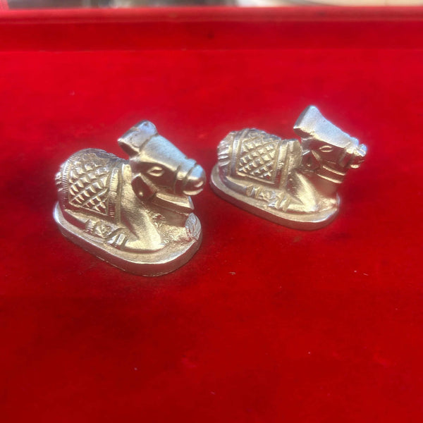 Pair of metal Nandi bull figurines, opposite side angles with patterned saddles, silver