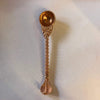 Ornate copper pooja spoon with domed bowl, decorative mesh top, and bead handle