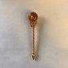 Copper puja spoon with decorative drop-shaped bowl and twisted rope-like handle.