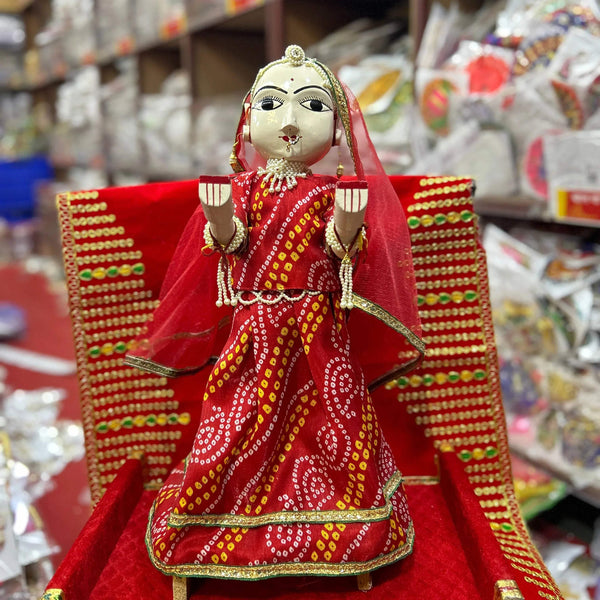 Wooden idol female doll with red veil and crown, red-and-gold dress, hands raised on base.