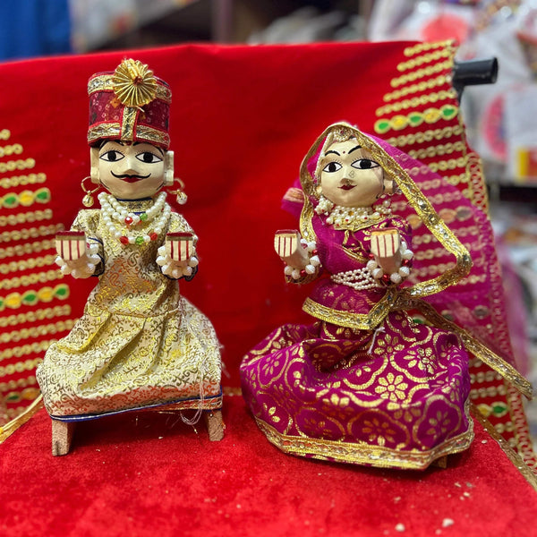 Wooden Radha-Krishna pooja idols, gold jewelry on red cloth