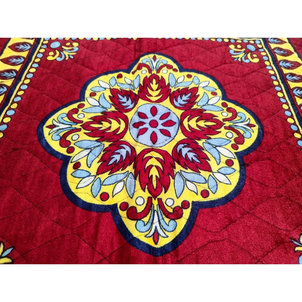 Close-up velvet mandir mat: central floral motif in red, gold and blue on maroon