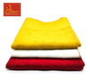 Woolen pooja mat set stacked: yellow mat with stitched edge over white and red