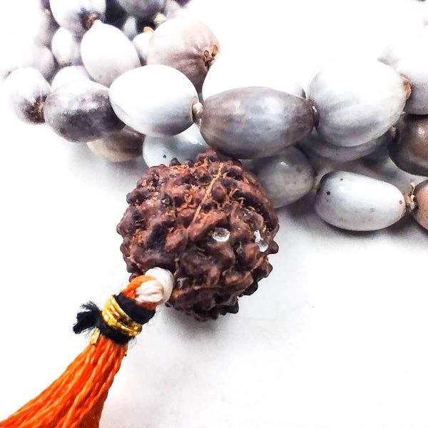 Close-up of stone bead mala with dark brown centerpiece and orange tassel